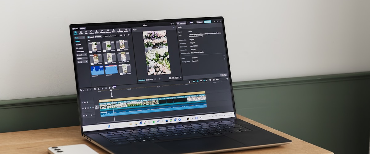 木製デスクに置かれたノートパソコンに動画編集ソフトのタイムラインが表示されている様子